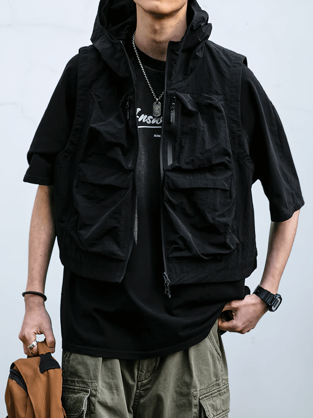 Man wearing a stylish black multi-pocket waterproof cargo vest with hood, perfect for outdoor activities.