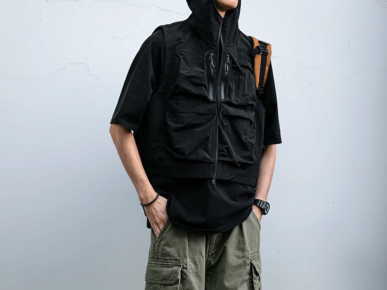 Man wearing black waterproof cargo vest SF2279 with hood, featuring multiple pockets, outdoors - perfect for adventure enthusiasts.