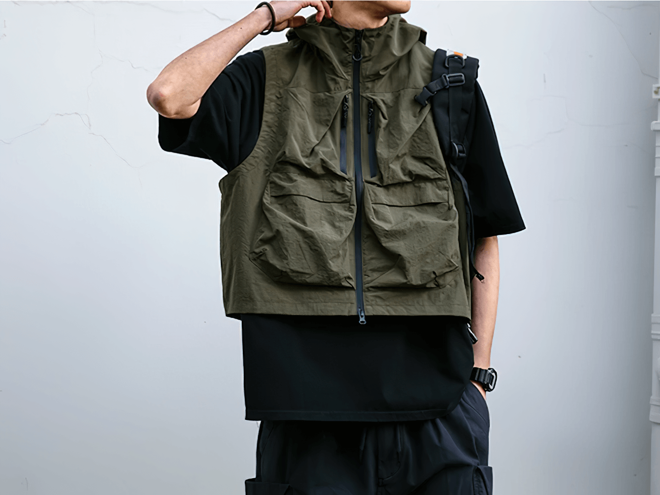 Man wearing a stylish, waterproof, multi-pocket cargo vest with hood, perfect for outdoor activities and adventures.