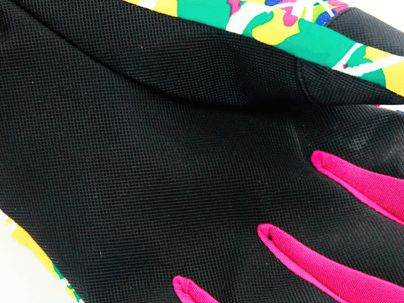 Close-up of multicolor waterproof snowboarding ski gloves showing pink fingers and vibrant design, ideal for winter sports.