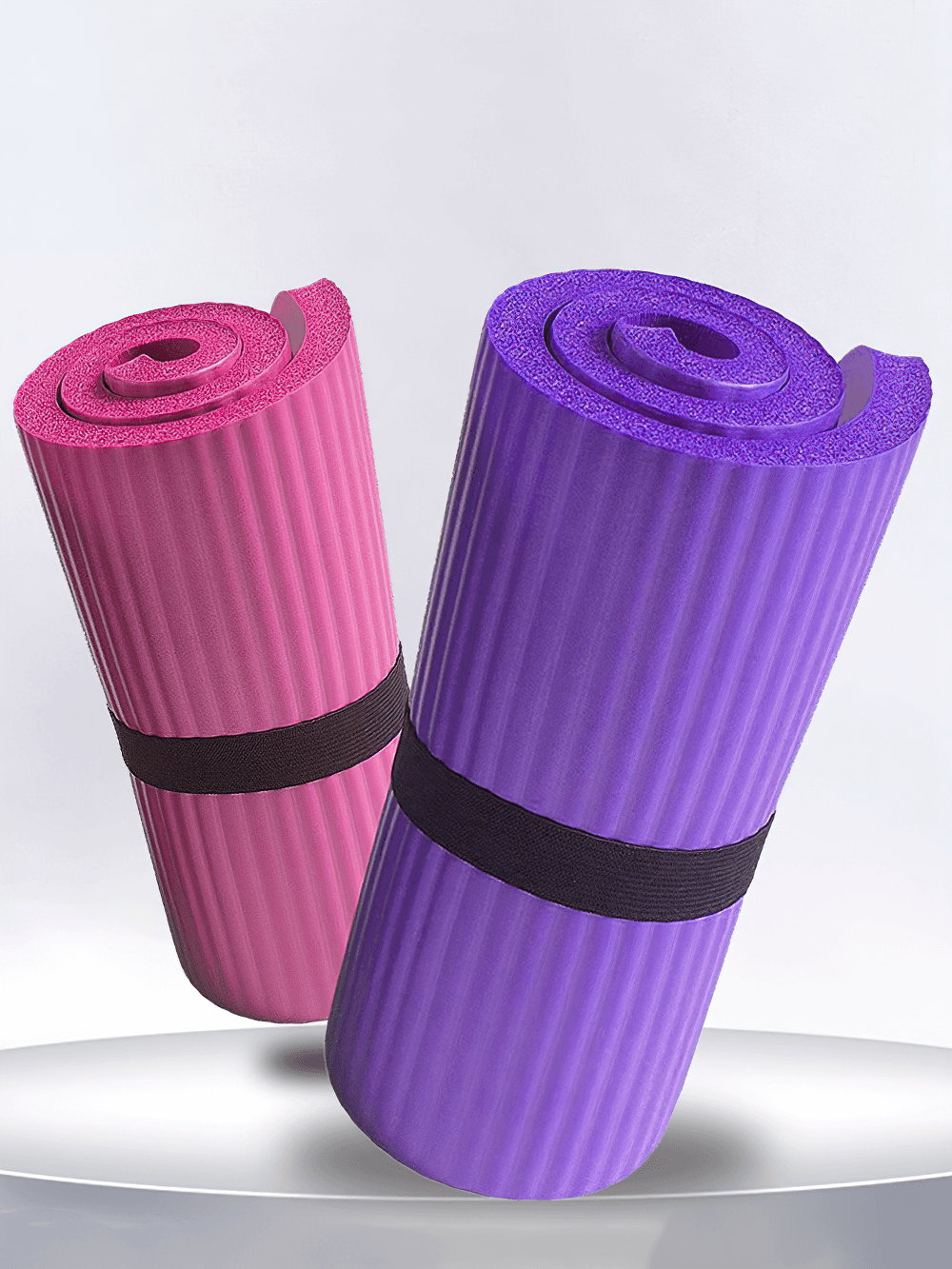 Two rolled non-slip EVA yoga mats in pink and purple with anti-slip stripes and honeycomb texture on a white surface.