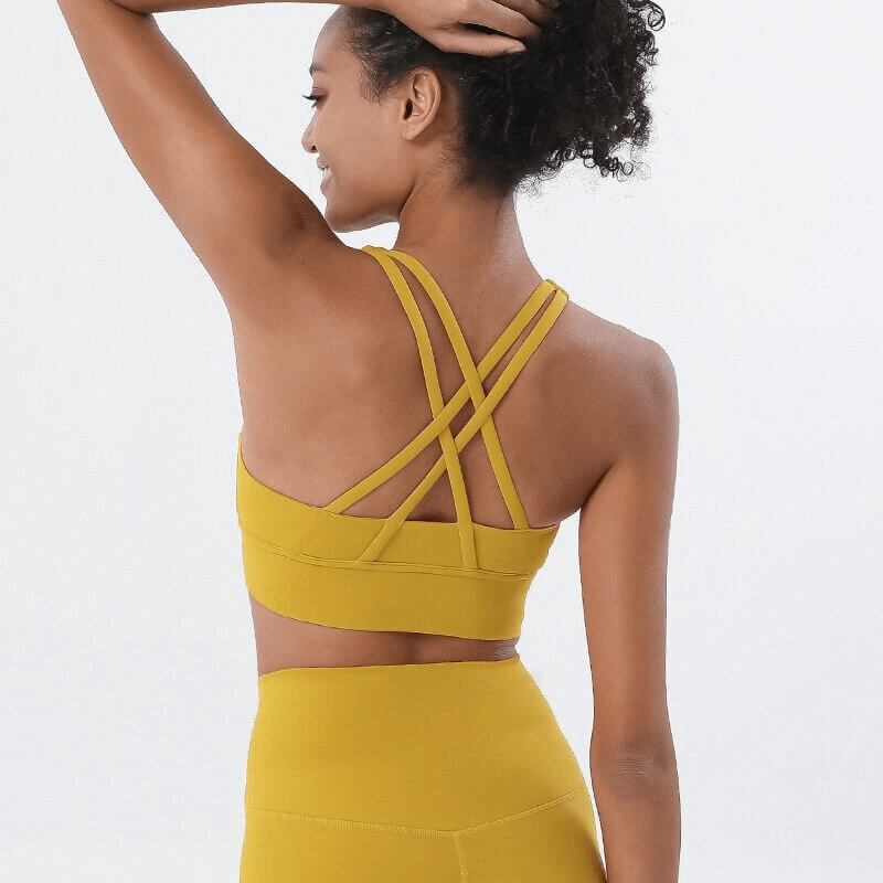 Back view of woman wearing yellow nylon sports top with cross shoulder straps, designed for yoga and fitness. Product code SF0036.