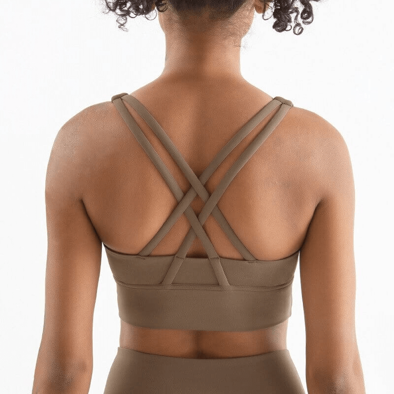 Back view of a woman wearing a nylon sports top with cross shoulder straps, showcasing the brown skinny stretch fitness bra design.