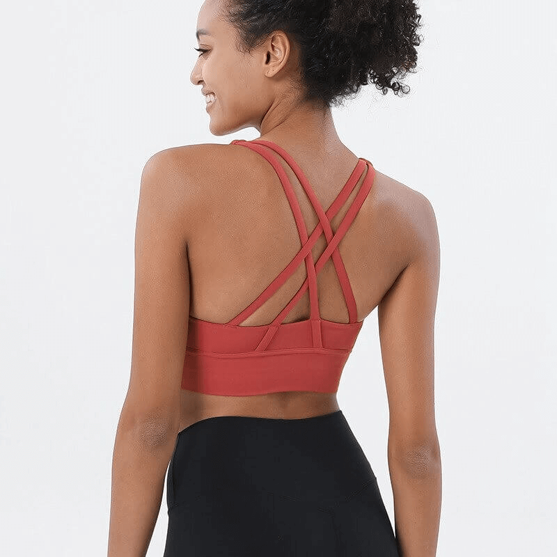 Woman wearing nylon sports top with cross shoulder straps, perfect for yoga and fitness. Ideal stretch fit, breathable, red color. Product SF0036