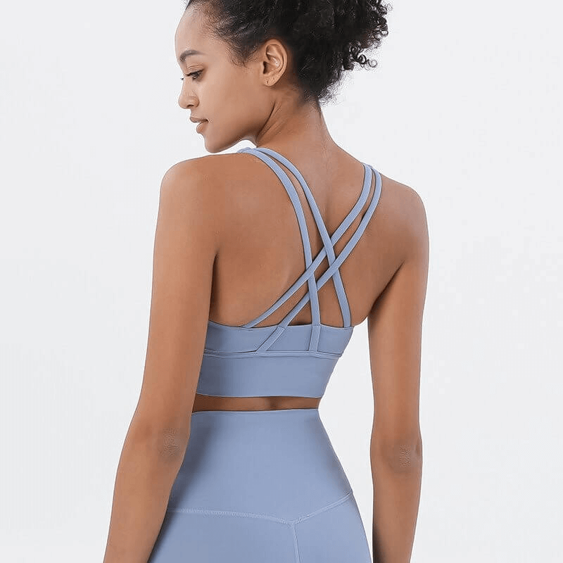 Woman wearing a steel blue nylon sports top with cross shoulder straps, perfect for fitness and yoga.