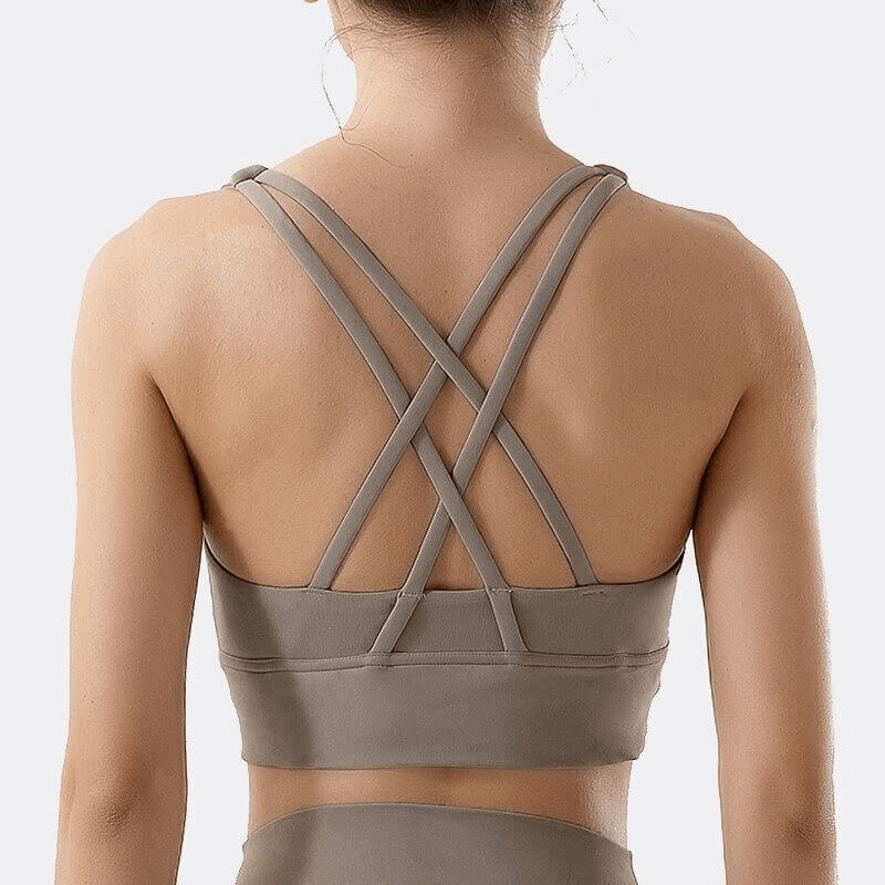 Woman wearing back view of nylon sports top with cross shoulder straps, ideal for yoga, gym, and running. Stylish and comfortable fit.