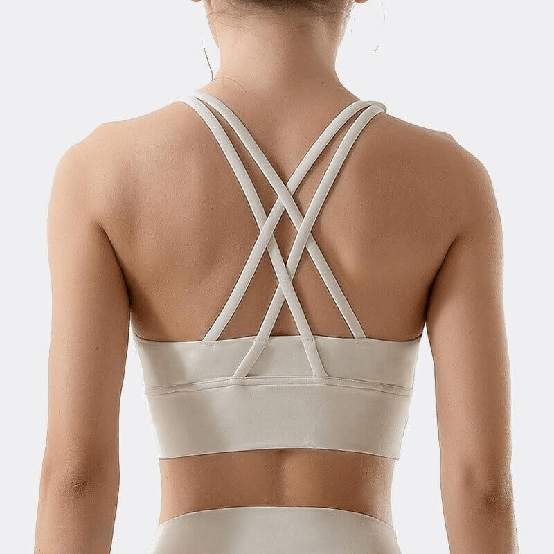 Woman wearing a nylon sports top with cross-shoulder straps, designed for yoga, gym, and fitness activities.