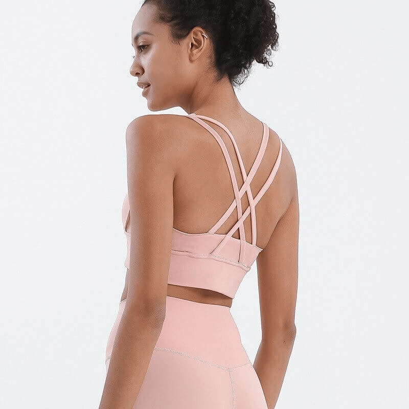 Woman wearing pink nylon sports top with cross shoulder straps, slim fit, ideal for gym and yoga. Model SF0036 fitness bra back view.