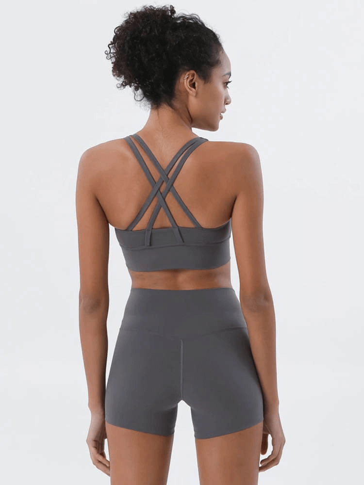 Back view of woman in nylon sports top with cross shoulder straps, perfect for yoga and fitness. Breathable and stretchy for comfort.