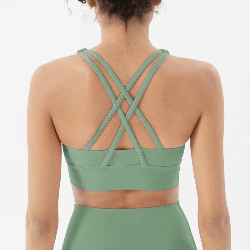 Back view of nylon sports top with cross shoulder straps for women, featuring skinny stretch fit in green color, perfect for workouts.
