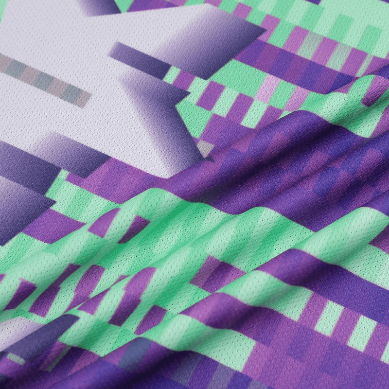 Close-up of purple and green geometric pattern on athletic polyester fabric, highlighting the vibrant design and breathable texture.
