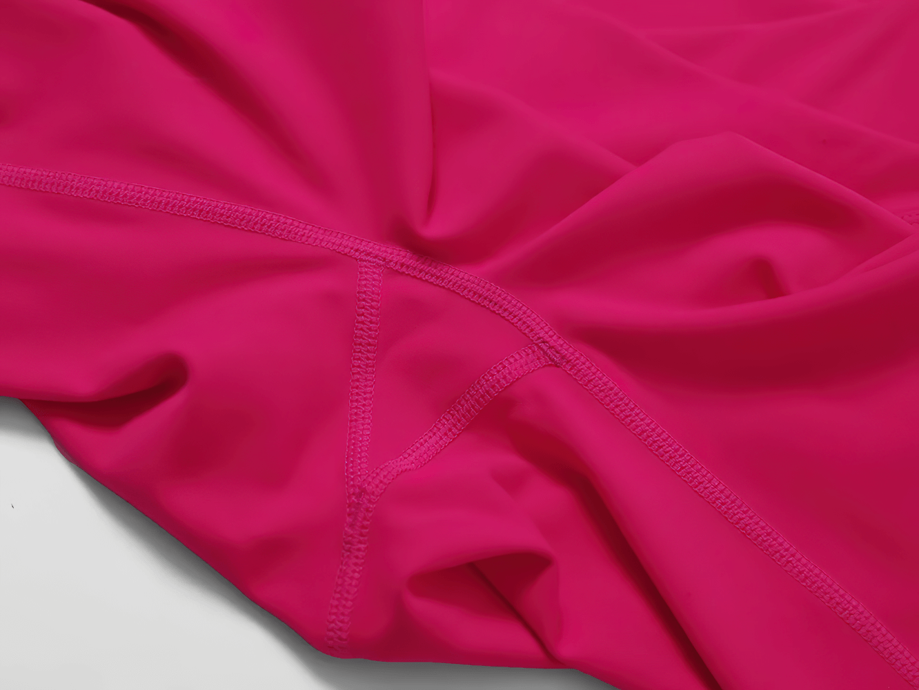 Close-up of vibrant pink activewear fabric, showing detailed stitching and smooth texture for yoga and fitness.