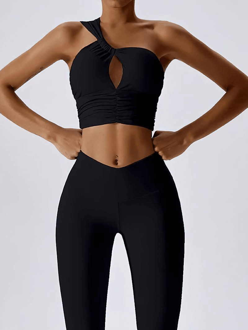 Woman wearing black one shoulder backless sports bra made of breathable Nylon and Spandex, ideal for yoga and fitness.