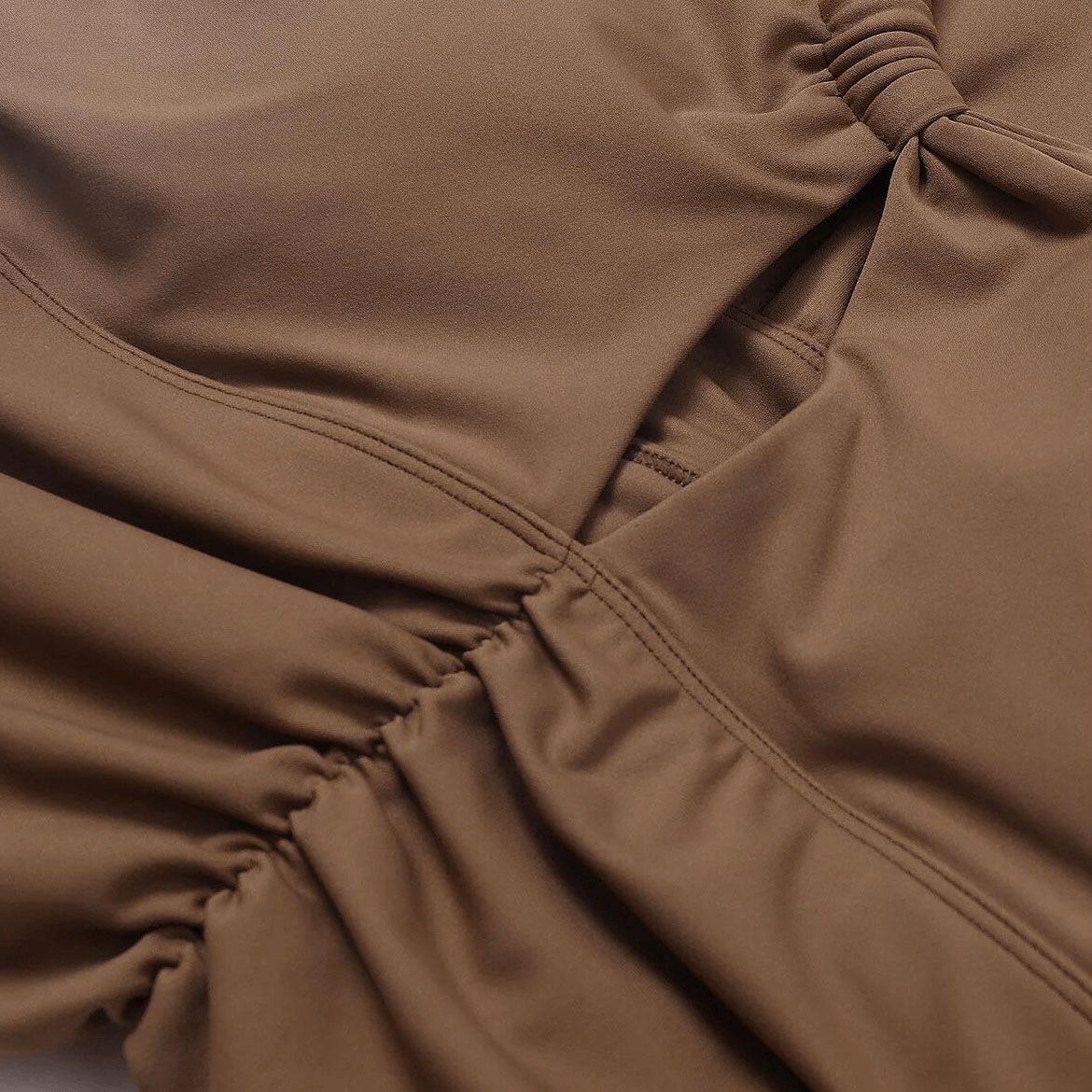 Close-up of a brown one shoulder backless fitness yoga sports bra fabric with adjustable straps and breathable nylon-spandex blend.