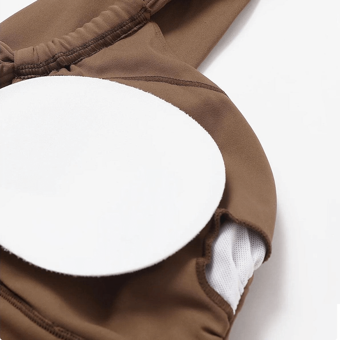 Close-up of brown one shoulder fitness sports bra with breathable nylon and spandex fabric and white padding detail.