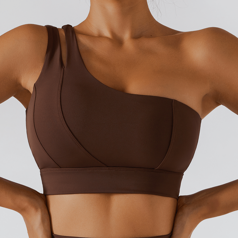 Woman wearing brown one-shoulder push-up sports bra, perfect for yoga and fitness. Breathable nylon-spandex design for movement.
