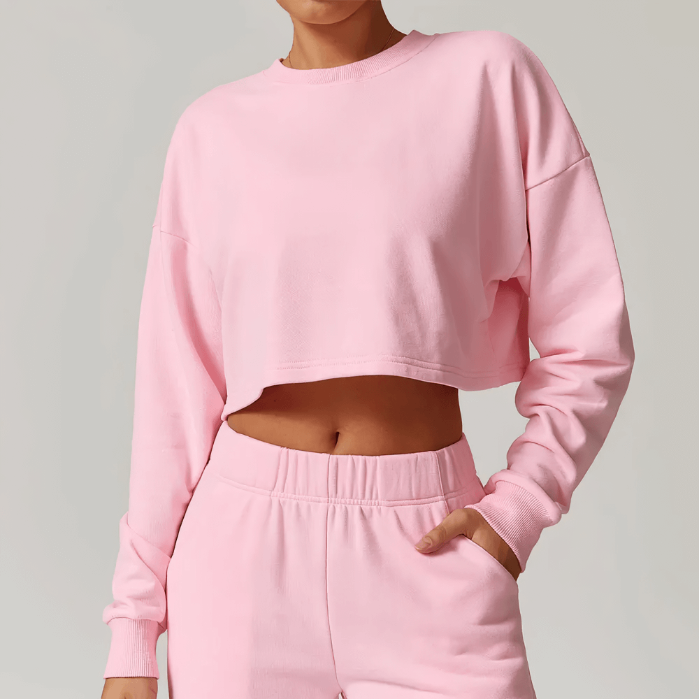 Stylish pink cropped sweatshirt with long sleeves and a relaxed fit, perfect for casual wear or lounging, modeled by a person.
