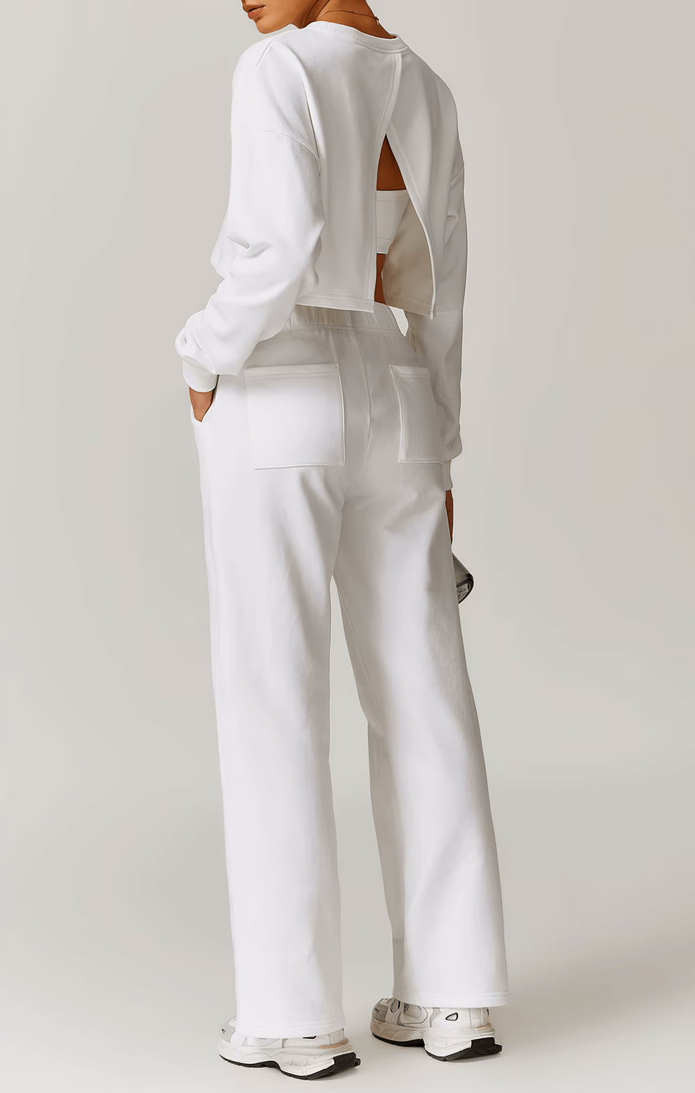 Woman wearing white open-back long sleeve sweatshirt and pants for active wear