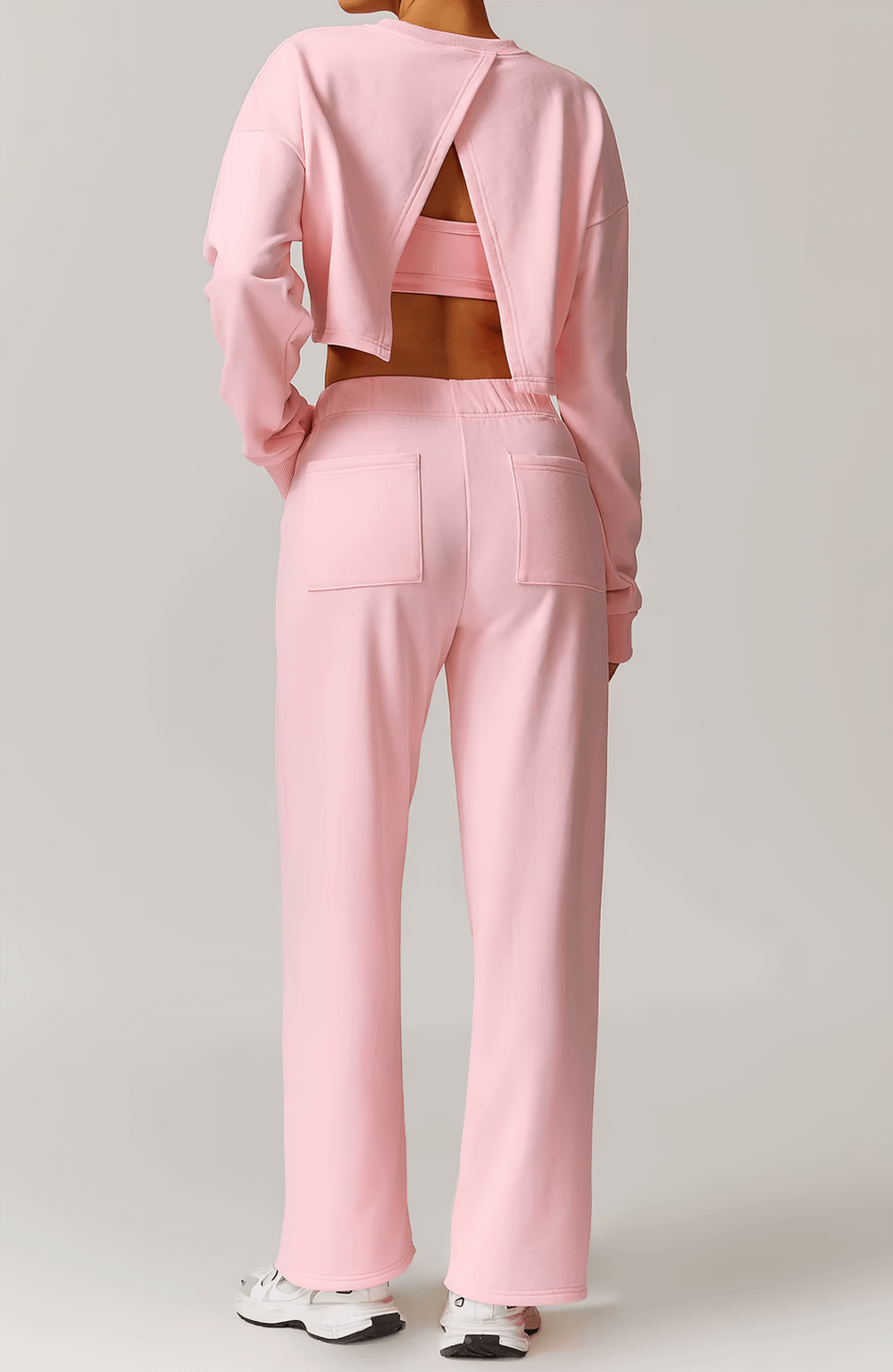 Back view of a pink open-back long sleeve sweatshirt paired with matching pants, showcasing stylish activewear for women.