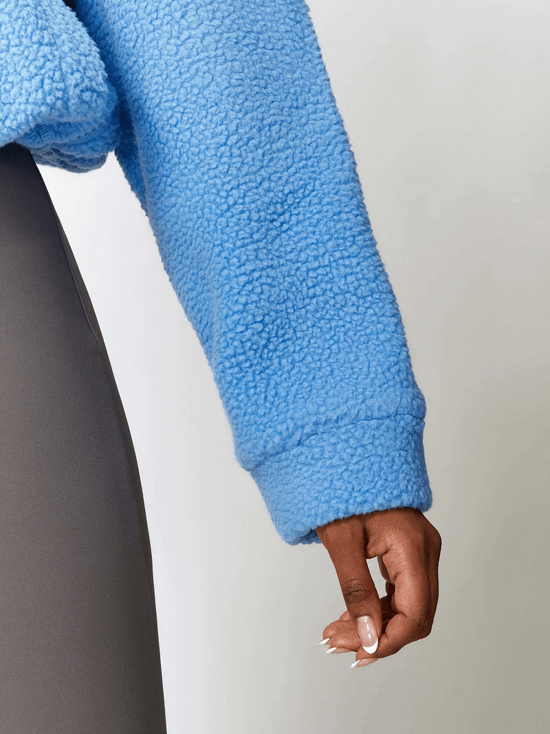 Close-up of a blue long-sleeve fleece jacket with a zipper, perfect for outdoor sports and yoga, highlighting soft, premium material.