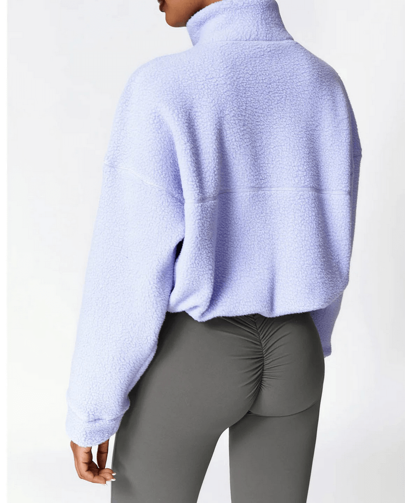 Woman wearing purple fleece sports jacket and gray leggings showcasing trendy outdoor activewear fashion.