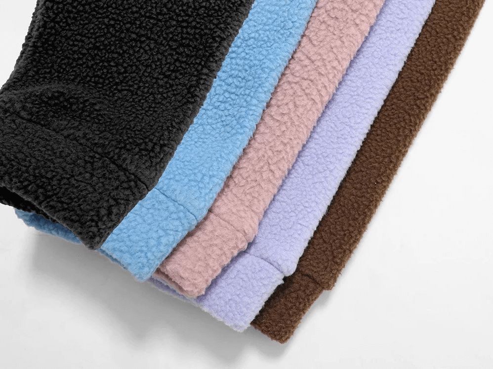 Stack of colorful fleece fabrics in black, blue, pink, purple, and brown, perfect for creating cozy sports jackets.