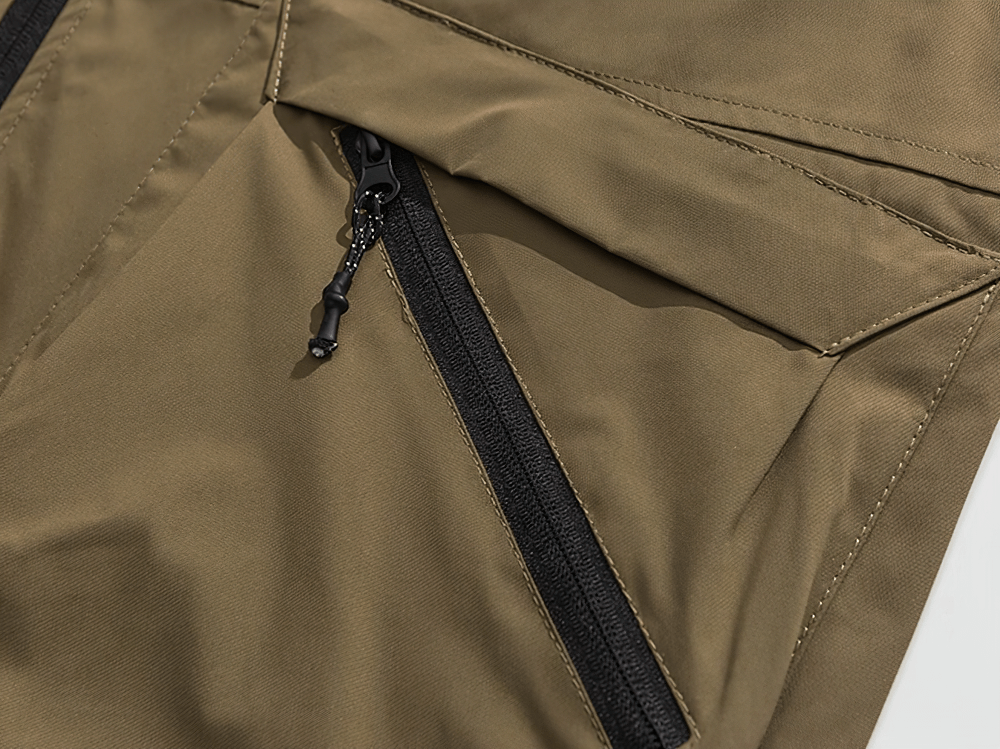 Close-up of brown tactical vest showcasing durable polyester fabric and secure zippered pocket, perfect for fishing and hiking adventures.