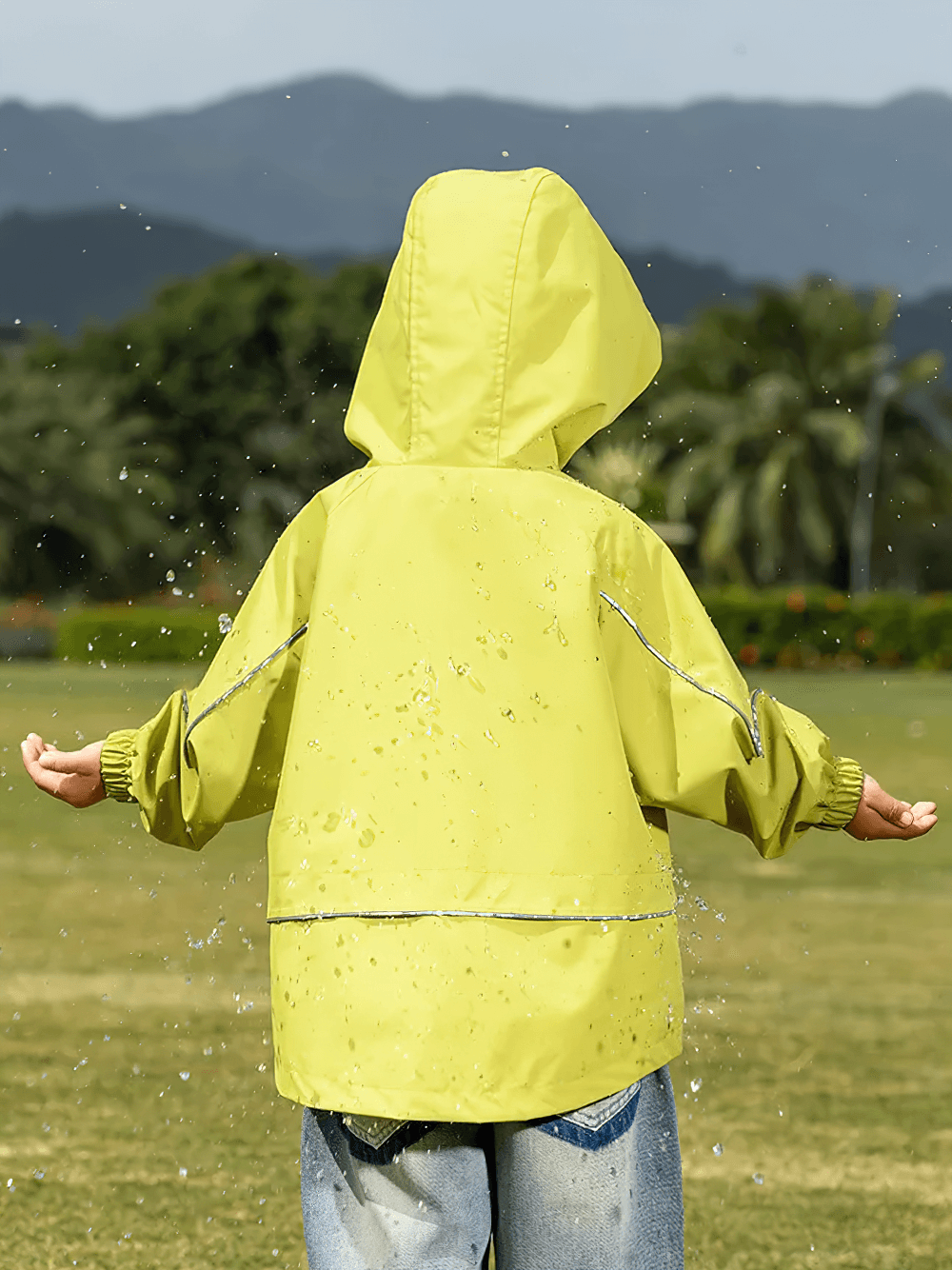 Child wearing Outdoor Waterproof Children's Windbreaker Jacket - SF3571 in vibrant yellow, enjoying a rainy day outdoors.