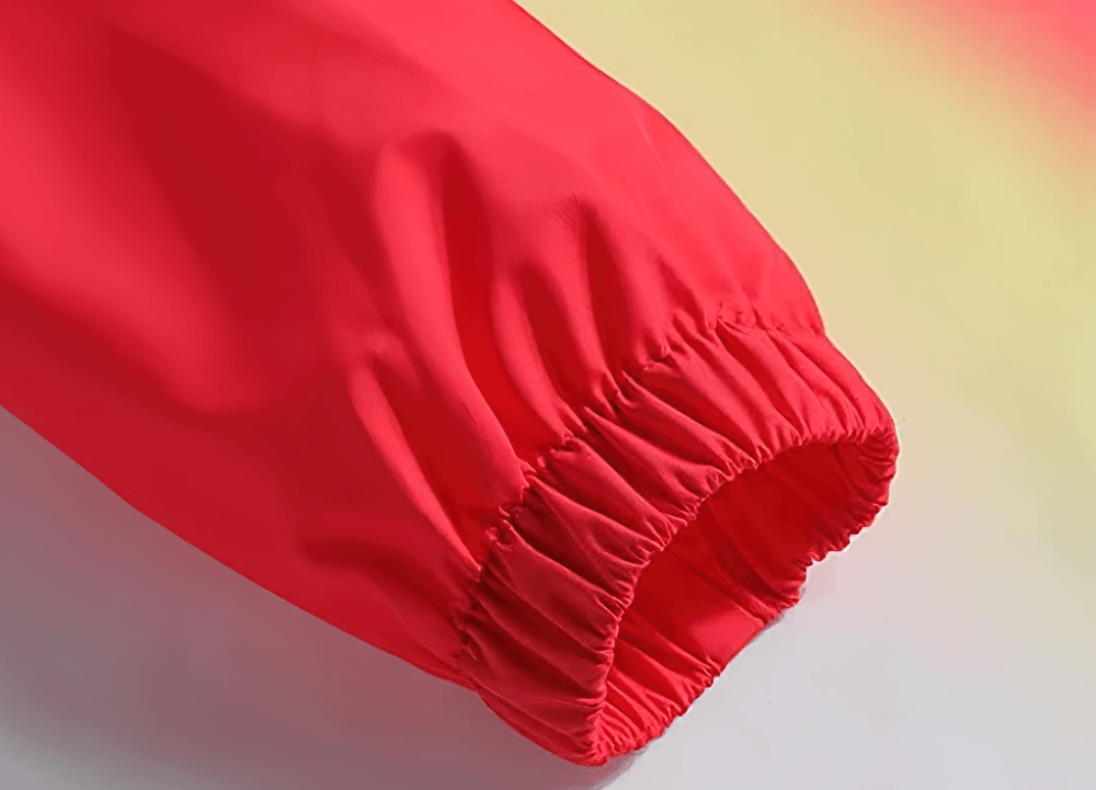 Close-up of red gradient waterproof sports jacket sleeve with elastic cuffs for wind protection.