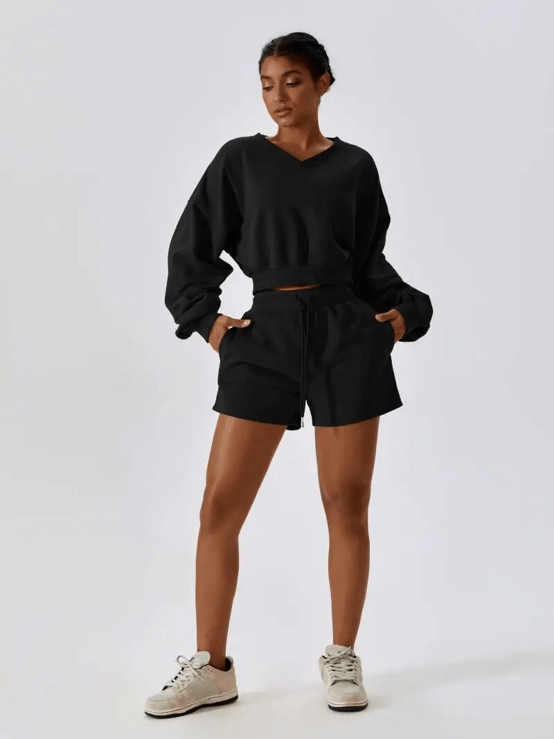 Woman wearing black cotton loose sweatshirt and shorts set, perfect for yoga and workouts, showcasing comfort and flexibility.