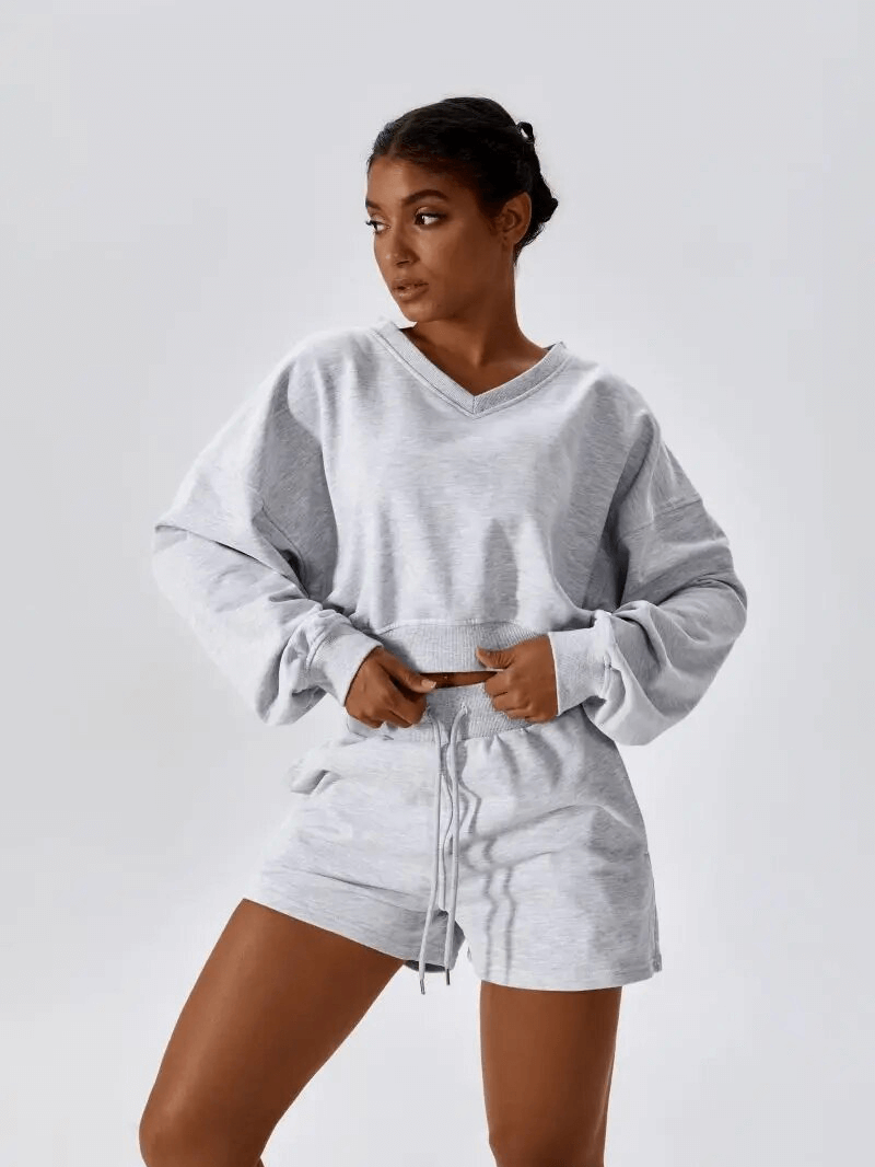 Woman wearing a comfortable gray cotton fitness sweatshirt and shorts set for yoga.
