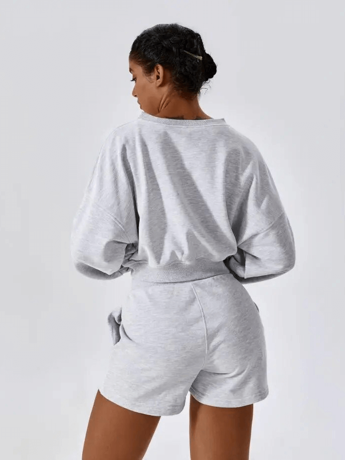 Woman wearing gray cotton sweatshirt and shorts set designed for yoga comfort and flexibility.