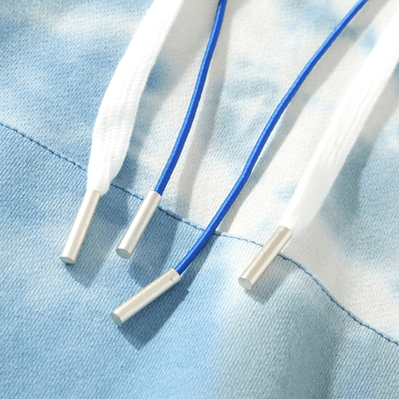 Close-up of blue and white drawstrings on a cotton hoodie, showcasing detailed stitching and dye pattern. Perfect blend of style and comfort.