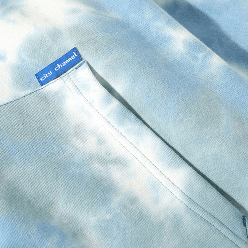 Close-up of a tie-dye cotton hoodie with a blue label, showcasing soft fabric and pocket detail, perfect for a casual and comfy style.