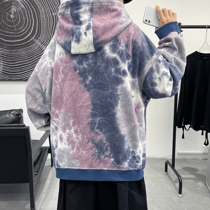 Man wearing oversized tie-dye cotton hoodie with hood, relaxed fit for a casual look in a modern room.