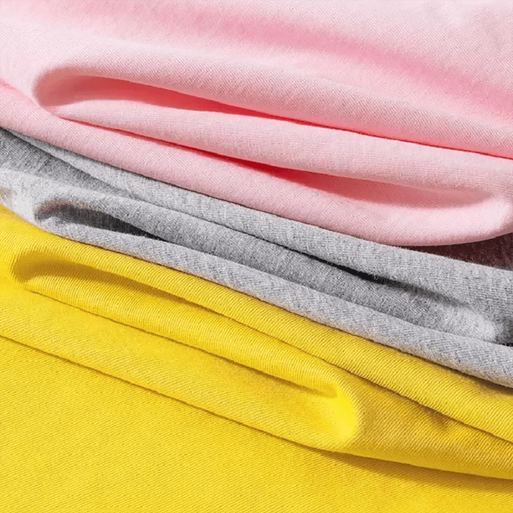 Stack of colorful cotton fabric in pink, gray, and yellow hues, showcasing soft material texture.