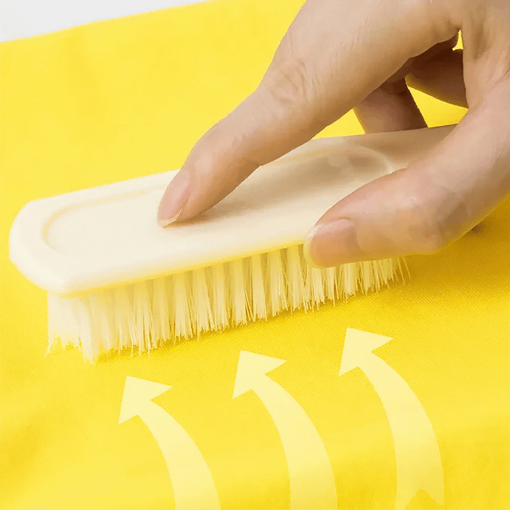Hand using a cleaning brush on a yellow surface with arrow graphics