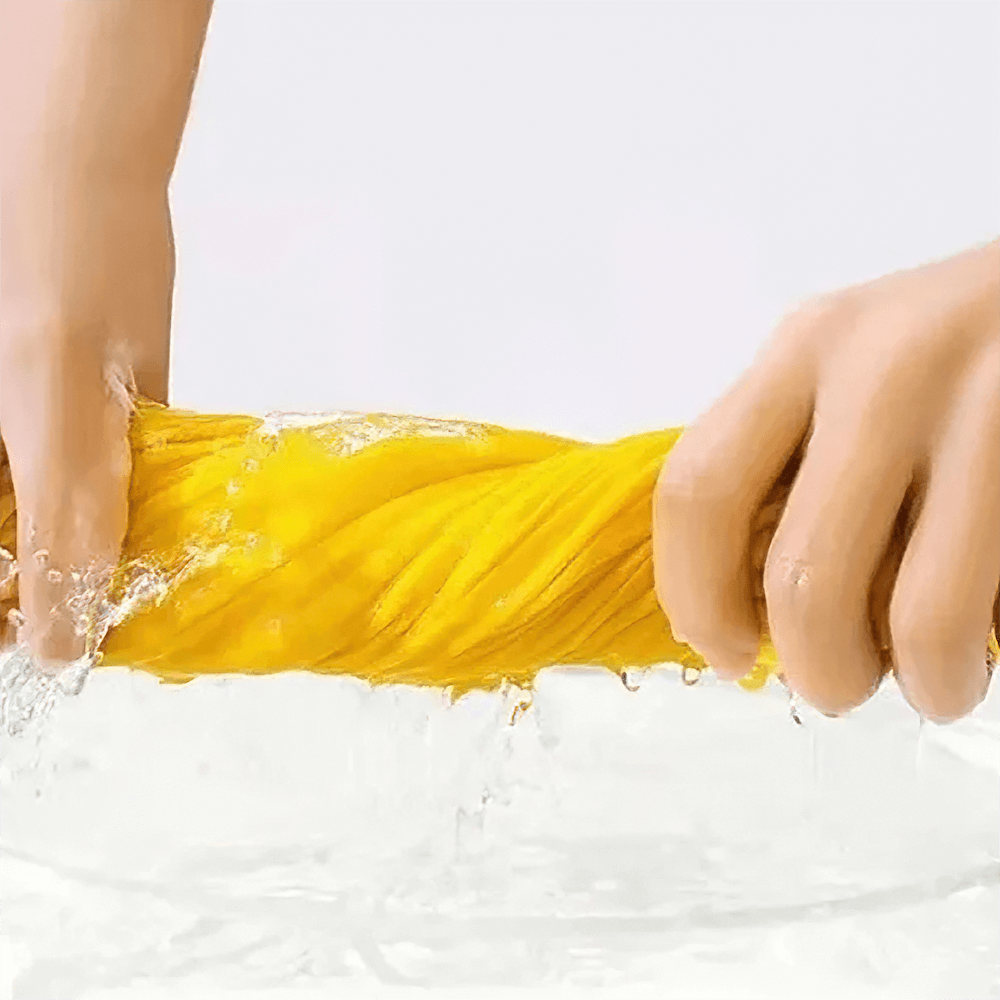 Hands wringing out a yellow cloth over water, showing effective absorption and drying.