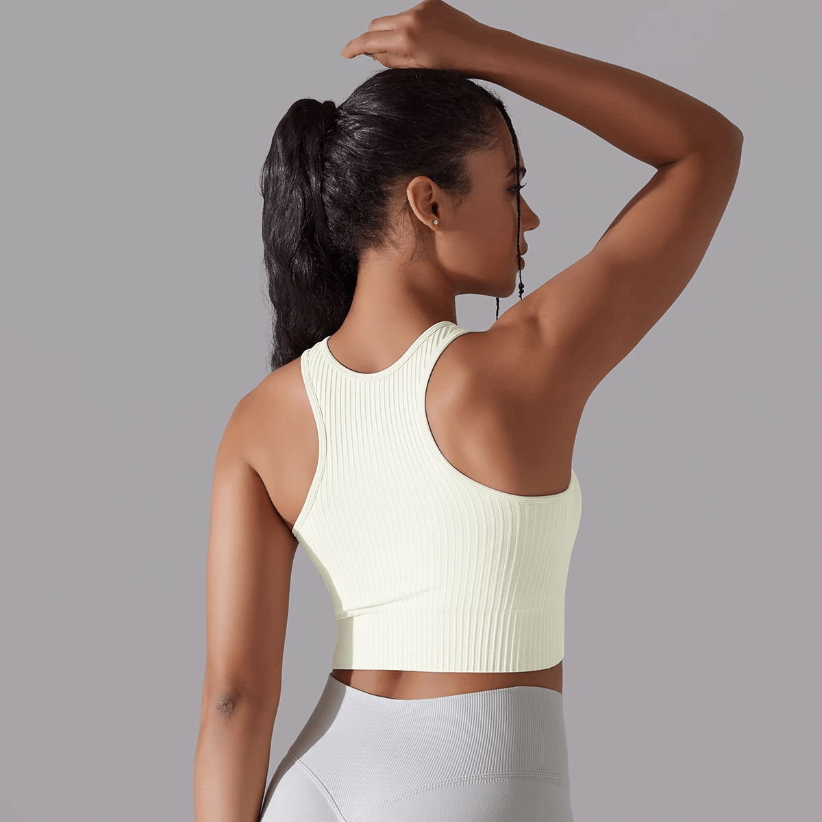 Woman in ribbed yoga short tank top, side profile view, wearing stylish activewear for yoga and fitness, showcasing snug fit and movement.