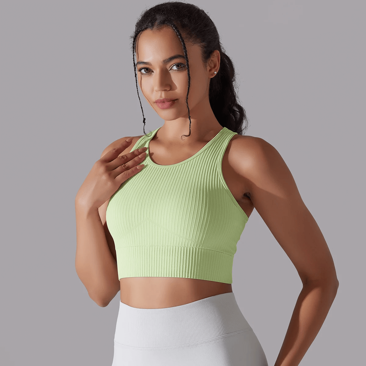 Woman wearing a green ribbed yoga short tank top, ideal for active sports and yoga sessions.