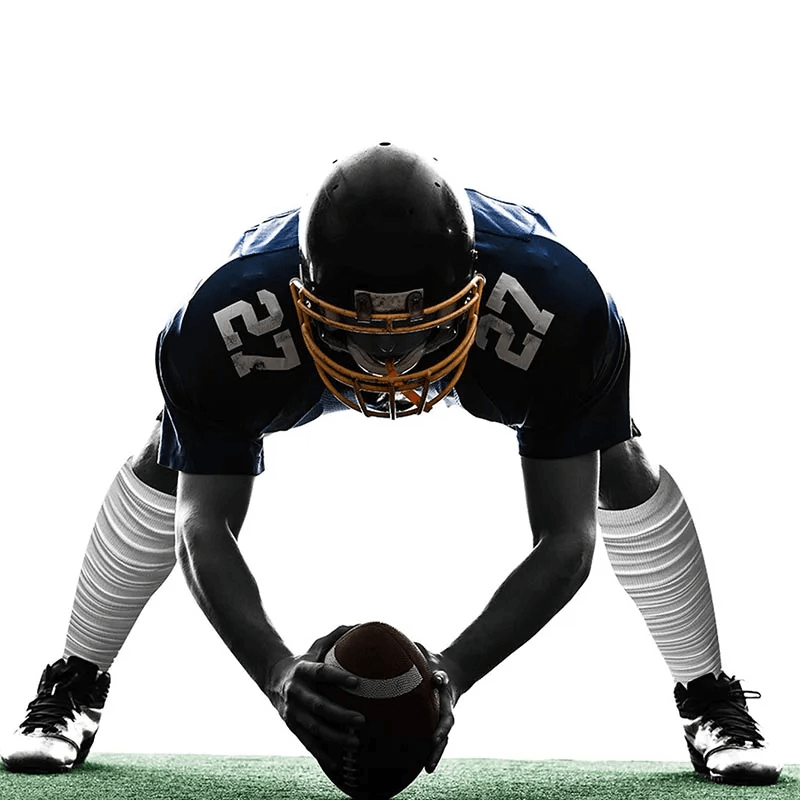 Football player in full gear wearing knee-high socks, ready to hike a football. Perfect display of durability and athleticism.
