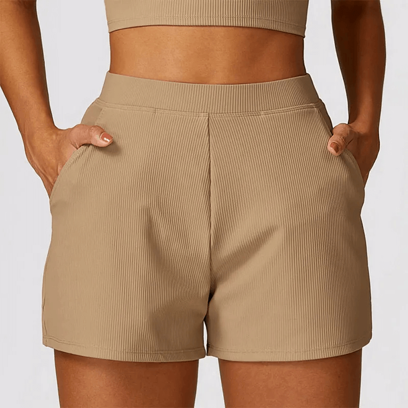 Tan ribbed high waist workout shorts for women with side pockets, perfect for yoga and gym sessions. Moisture-wicking fabric.