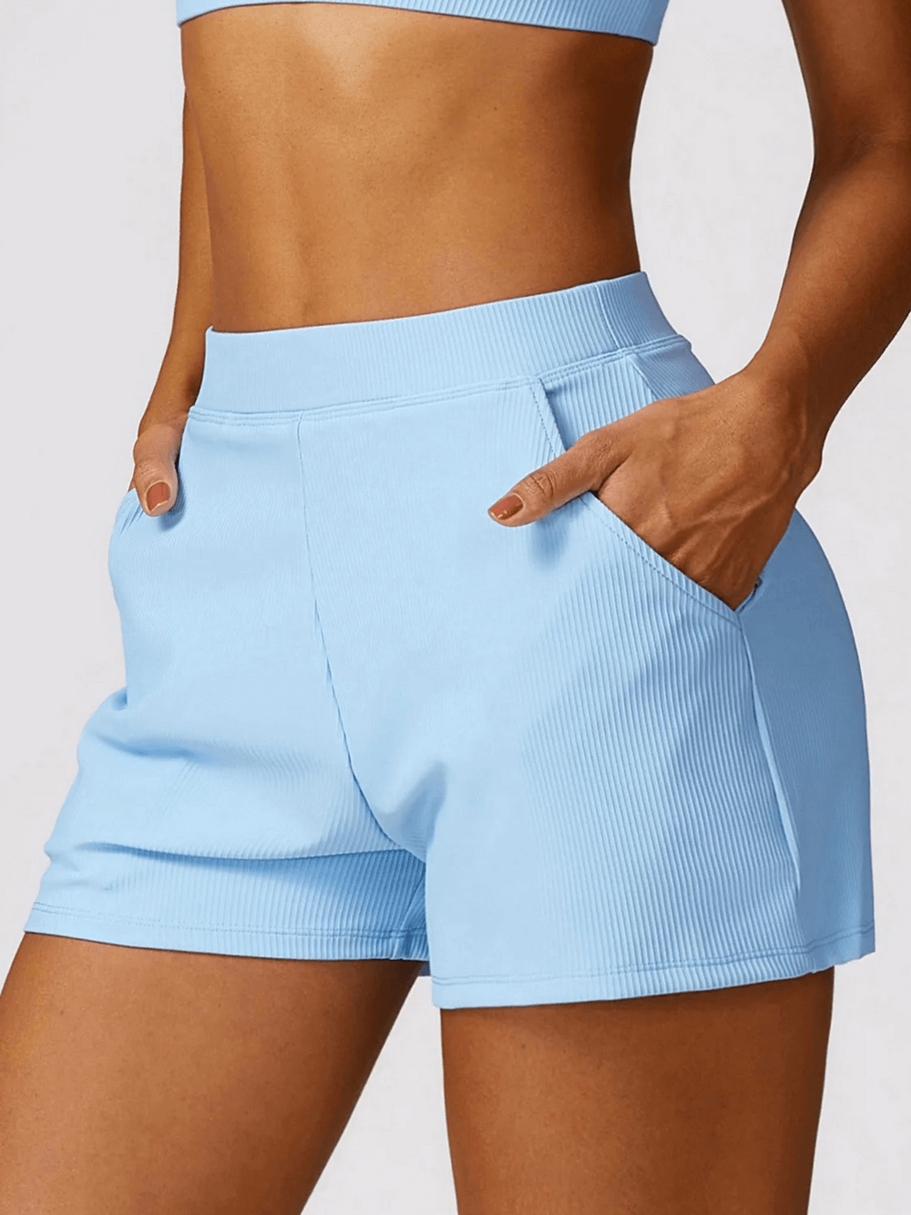 Woman wearing blue high-waist workout shorts with ribbed waistband and side pockets for gym and yoga sessions, item SF2204.