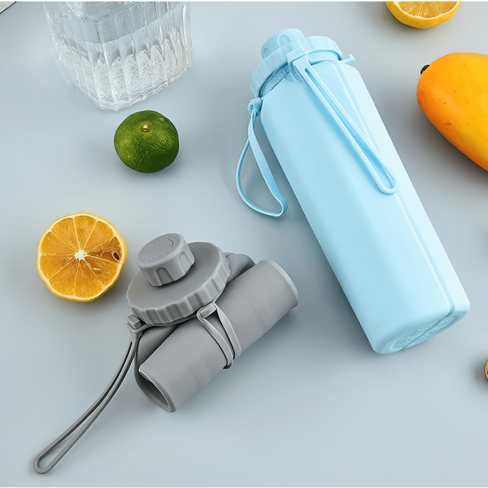 Light blue and grey Portable Collapsible Bottle for Travel and Gym - SF3490 with fruits on a table, showcasing its foldable design.