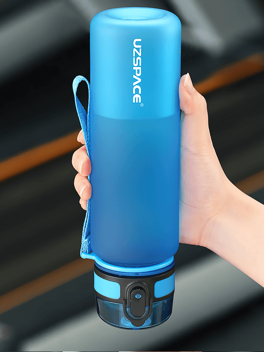 Blue portable leak-proof sports water bottle with strap, Tritan material, shown being held to highlight easy-open lid and durable design.
