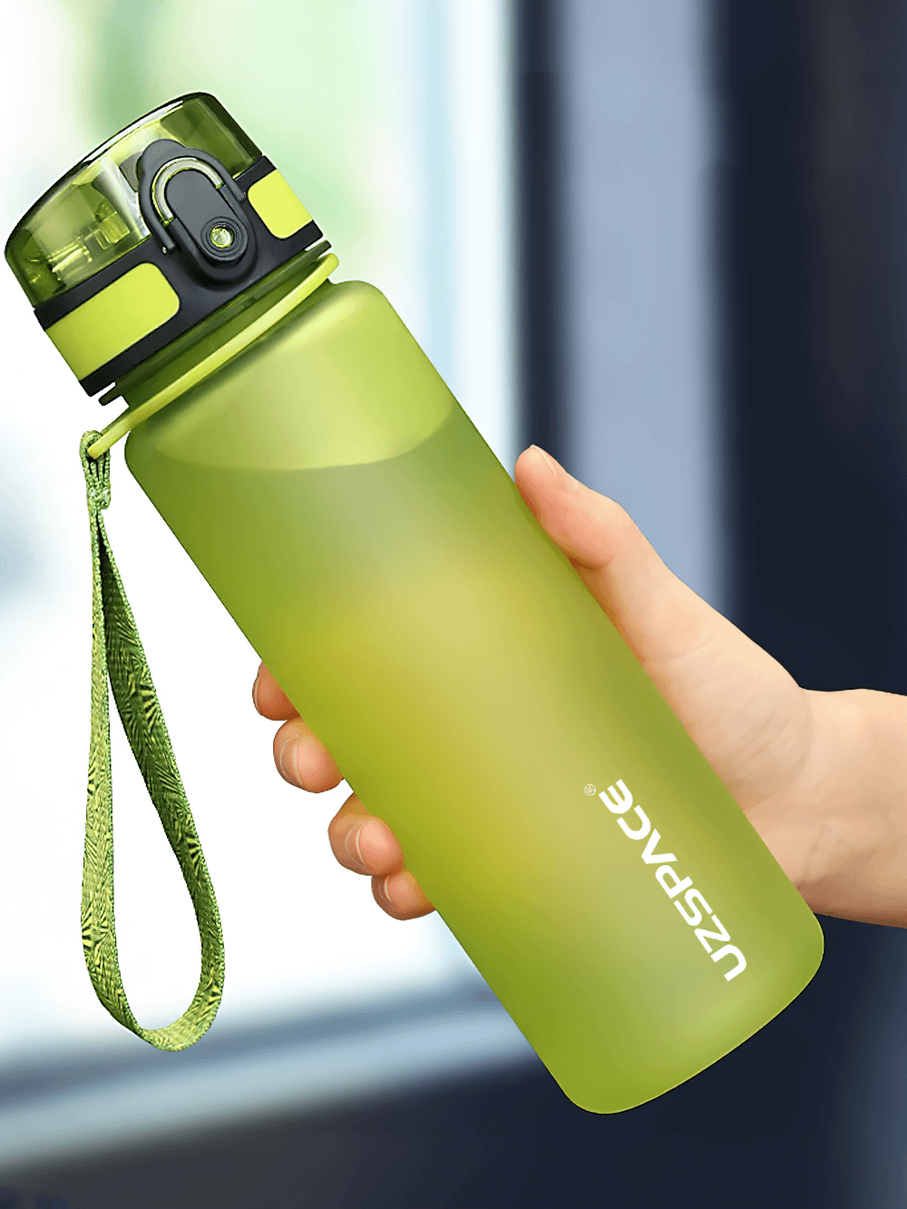 Person holding a green leak-proof sports water bottle with strap and easy-open lid, ideal for outdoor activities.