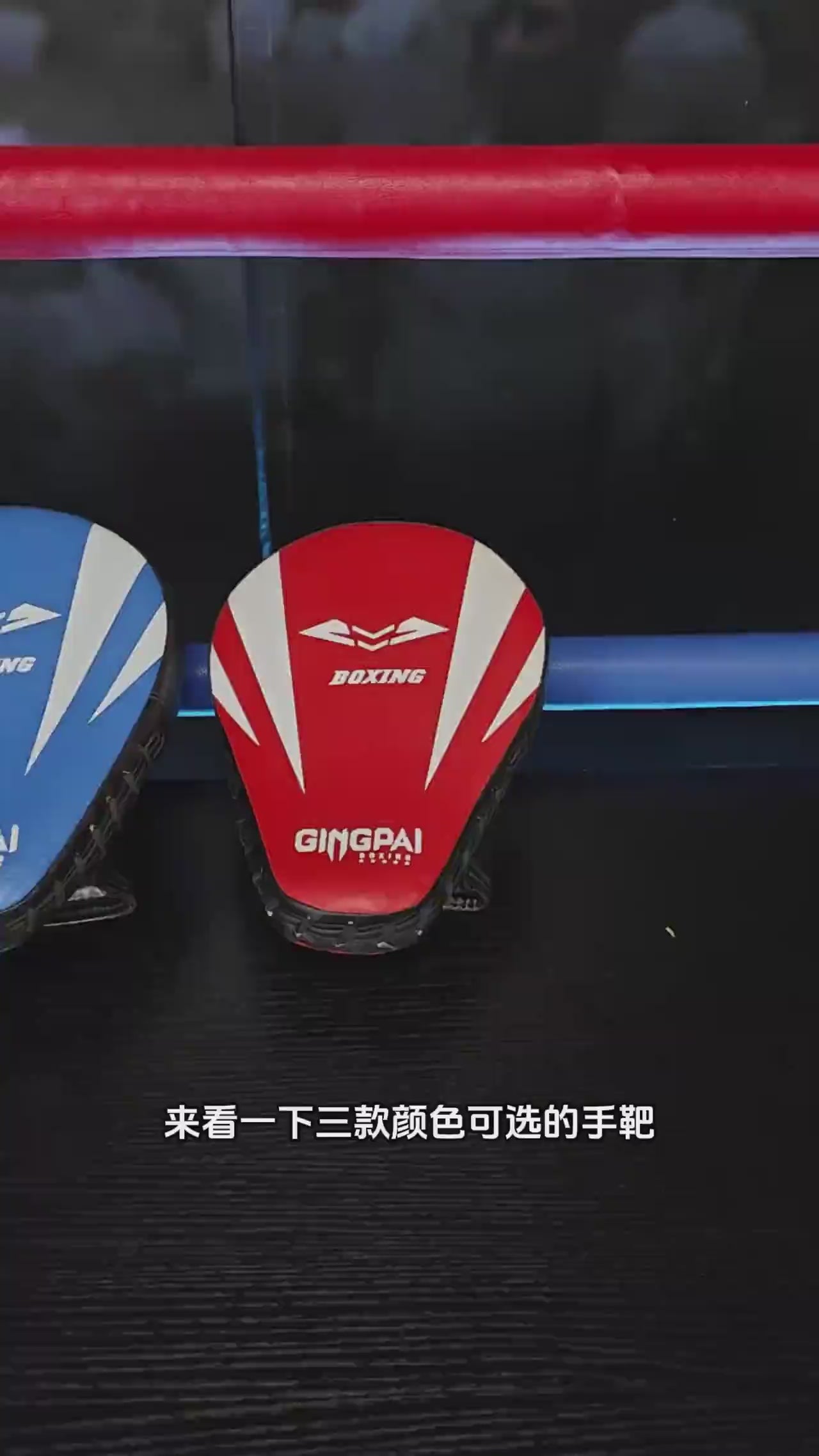 Red curved boxing focus pad with ergonomic hand grip for martial arts training displayed on shelf.