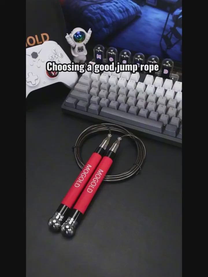 Jump rope with red handles on desk near keyboard and game controller, perfect for cardio and endurance training.