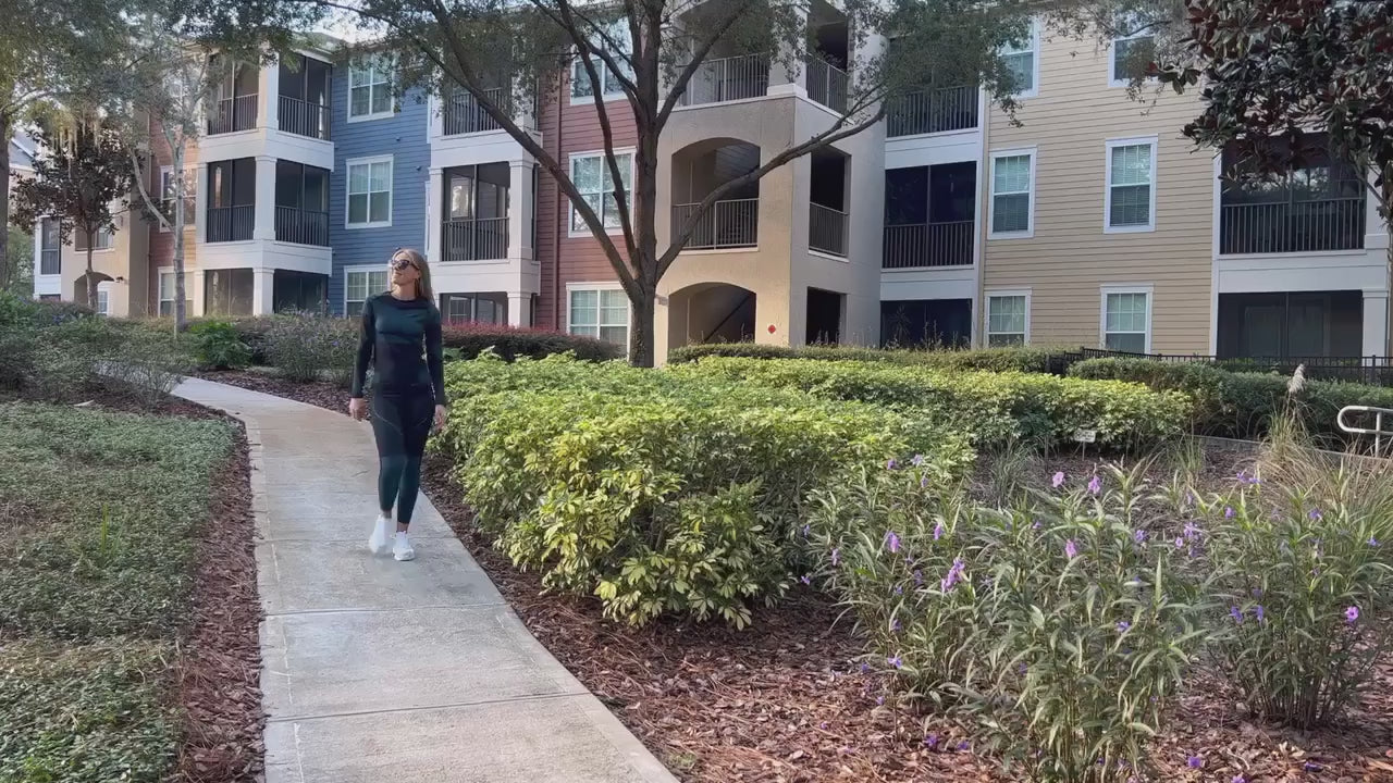 Person walking on a garden path in front of modern apartment buildings