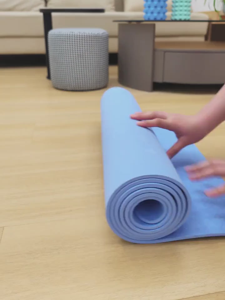 Person rolling up a non-slip blue yoga mat with textured surface for grip and stability, perfect for home workouts.